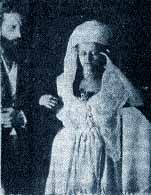 Sir William Crookes is seen standing arm in arm with Katie King, materialized spirit.